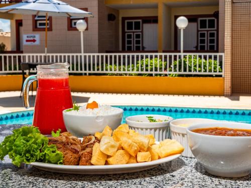 a table with a plate of food and a drink at Pousada Mares em Sergipe in Estância