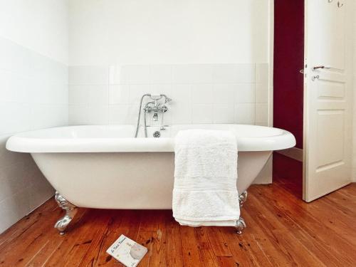 y baño con bañera blanca y suelo de madera. en Petit château Le Piot, en Fleurance