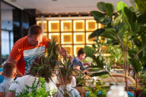 a man standing at a table in a restaurant at Royal G Max in Golem