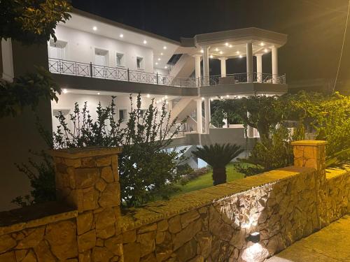 a large white house with a stone wall at night at Staikos in Ligia