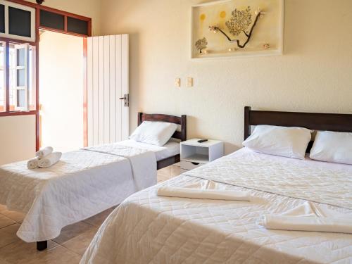 a hotel room with two beds with white sheets at Pousada Mares em Sergipe in Estância