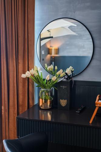 a vase of flowers on a table with a mirror at Royal G Max in Golem