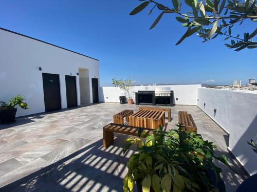 マサトランにあるCondo in El Centro Near Malecon!の建物の屋上に2つの木製のベンチがあるパティオ