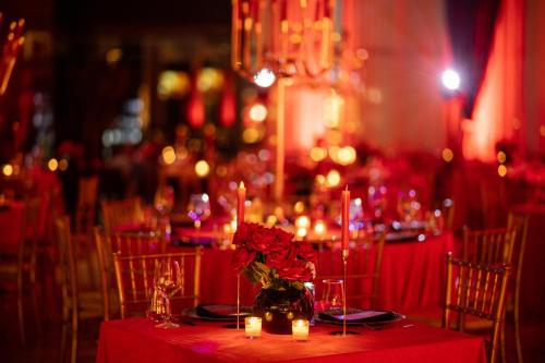 a table with a red table cloth with candles and flowers at Royal G Max in Golem