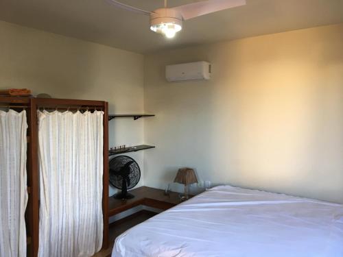 1 dormitorio con 1 cama con sábanas blancas y ventilador en Casa familiar, en Arraial do Cabo