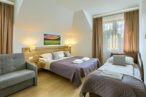 una habitación de hotel con 2 camas y una silla en Willa u Alicji i Jana, en Tylicz