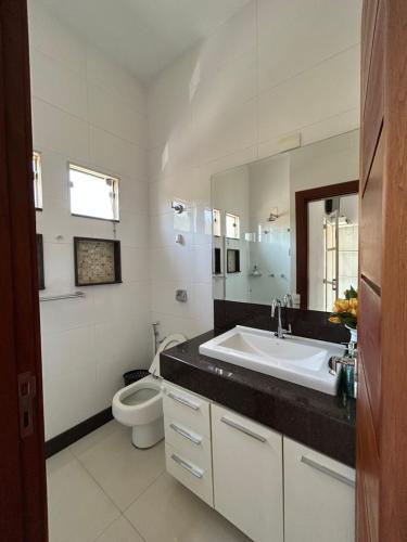 a white bathroom with a sink and a toilet at Suites Silva in Capitólio