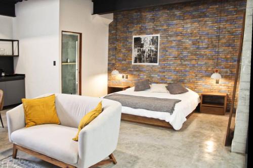 a bedroom with a bed and a couch and a brick wall at Loft hierro en excelente ubicación! in San Luis Potosí