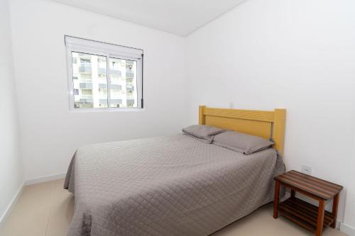 een witte slaapkamer met een bed en een raam bij 449 - Lindo Apartamento de 3 dormitórios á 80m da praia de Bombas in Bombinhas