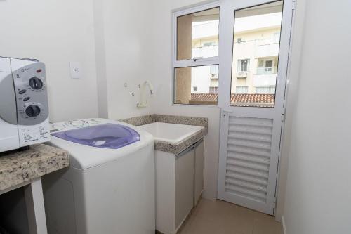 een badkamer met een toilet, een wastafel en een raam bij 449 - Lindo Apartamento de 3 dormitórios á 80m da praia de Bombas in Bombinhas