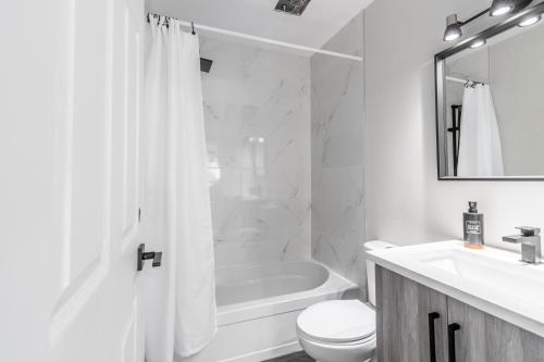 a white bathroom with a tub and a toilet and a sink at Hotel du lac by Rendez-Vous Mont-Tremblant in Mont-Tremblant