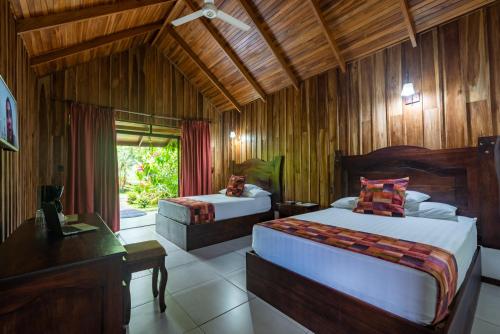 a bedroom with two beds and a desk and a window at Arenal History INN in Fortuna