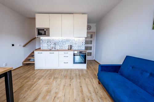 a living room with a blue couch and a kitchen at Wellness zoo apartmány Lhota in Lomnice nad Lužnicí