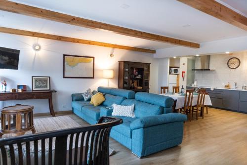 a living room with a blue couch and a kitchen at 1884 Aveiro Loft in Aveiro