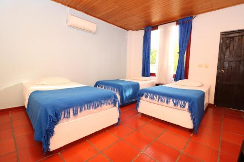 drie bedden in een kamer met blauw en wit bij Hotel y Parque Acuatico Agua Sol Alegria in Honda