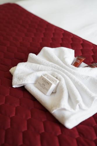 a white blanket on top of a red bed at Hotel Queanbeyan Canberra in Queanbeyan