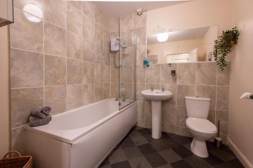 a bathroom with a toilet and a sink and a bath tub at 13 Victoria Road Apartment in Cardiff