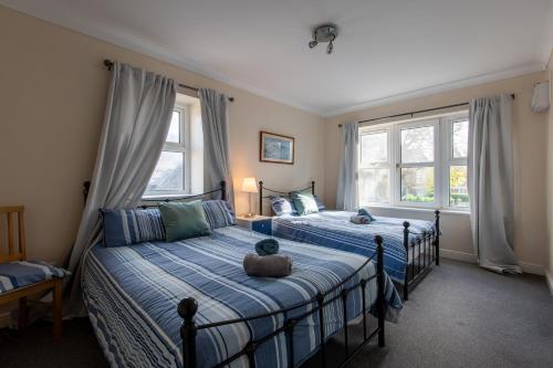 a bedroom with two beds and two windows at 13 Victoria Road Apartment in Cardiff