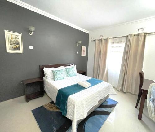 a bedroom with a bed with a blue and white blanket at Busisiwe's RM Home in Lusaka