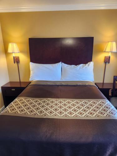 Galaxie Motel في Philomath: سرير في غرفة الفندق مع مصباحين