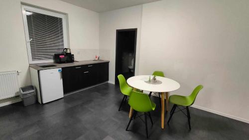 a kitchen with a table and green chairs in a room at Apartmány u golfu in Jihlava