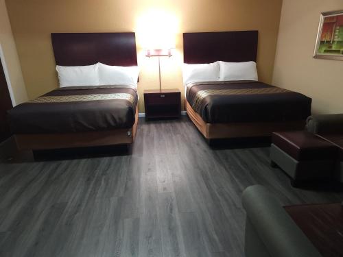 duas camas num quarto de hotel com pisos de madeira em Galaxie Motel em Philomath