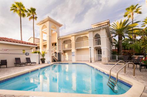 uma piscina em frente a uma casa com palmeiras em Best Western Seaside Inn em Saint Augustine Beach