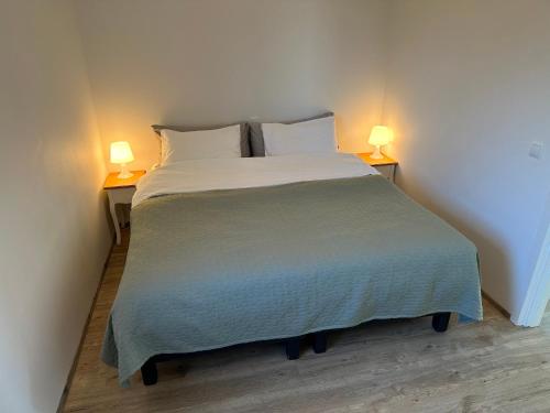 a bed in a room with two lamps on two tables at Farmer's Guest House in Hella