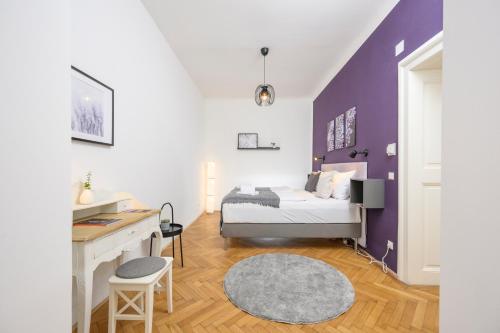 a bedroom with a bed with a desk and a purple wall at Central City Apartments in Vienna