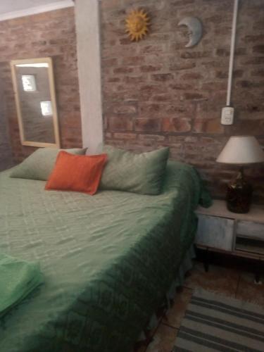 a bedroom with a bed and a brick wall at Lo de Guille in Oberá