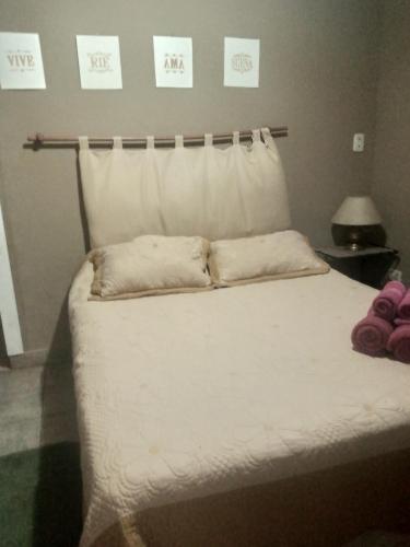 a white bed with two pillows on top of it at Lo de Guille in Oberá