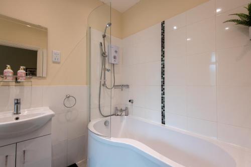 a white bathroom with a tub and a sink at Seaview Cottage in Cardiff