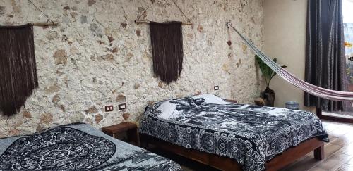 two beds in a room with a stone wall at Casa los Jarochos in Valladolid