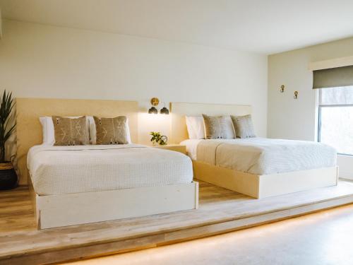 two beds in a bedroom with white walls and wood floors at Brut Hotel in Tulsa
