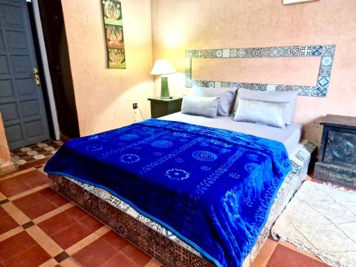 a bedroom with a bed with a blue blanket at Le Domaine de Carole Marrakech in Akkara