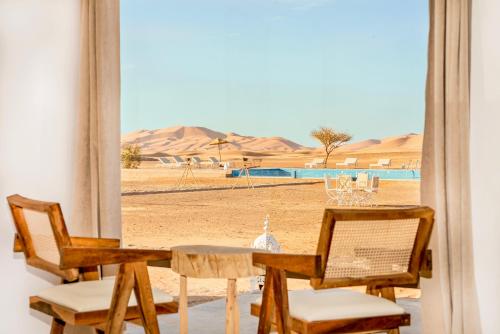 een tafel en stoelen met uitzicht op de woestijn bij Sahara Royal Resort in Merzouga