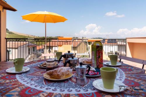 a table with plates of food and an umbrella on a balcony at Terrazza Sulla Luna in Casciana Terme