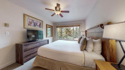 Villas at Snowmass Club في سنوماس فيليج: غرفة نوم بسرير مع مروحة سقف وتلفزيون