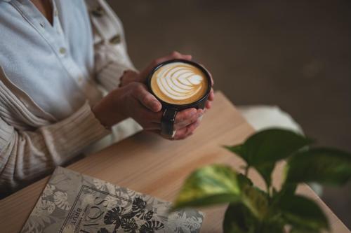 a woman is holding a cup of coffee at Brut Hotel in Tulsa