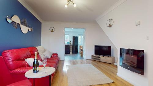 a living room with a red couch and a tv at Duxford Deluxe in Thriplow