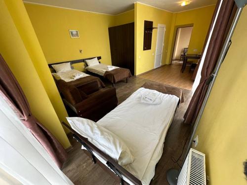 a room with two beds in a room with yellow walls at Hotel Cisar in Lviv