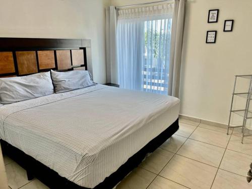 Un dormitorio con una cama grande y una ventana en Palmeira71, acogedora Casa en Privada de ValleAlto, en Bellavista