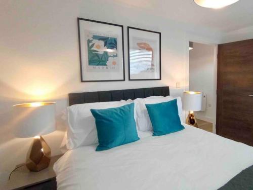 een slaapkamer met een groot wit bed met blauwe kussens bij Luxury 2 Bed 2 Bath Flat Near Old Trafford in Manchester