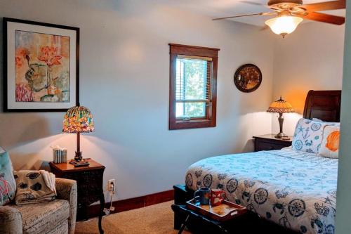 a bedroom with a bed and a chair and a window at Cottage on the Mississippi Venue and dog friendly in Le Claire