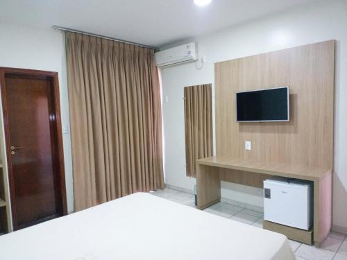 Habitación de hotel con cama y TV de pantalla plana. en Tawfiqs Hotel, en Barra do Garças