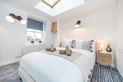 a white bedroom with a white bed and a window at Brick Lane Hub in London