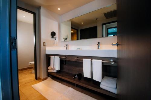 ein Badezimmer mit einem Waschbecken, einem Spiegel und Handtüchern in der Unterkunft Hilton Garden Inn Mexico City Santa Fe in Mexiko-Stadt