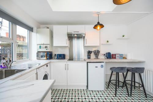 a kitchen with white cabinets and a sink and stools at Brick Lane Hub in London
