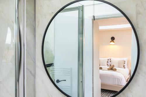 a round mirror in a bedroom with a bed at Verv Brick Lane in London