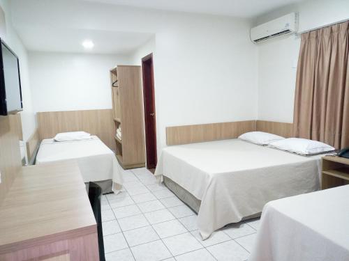 a hotel room with two beds and a tv at Tawfiqs Hotel in Barra do Garças